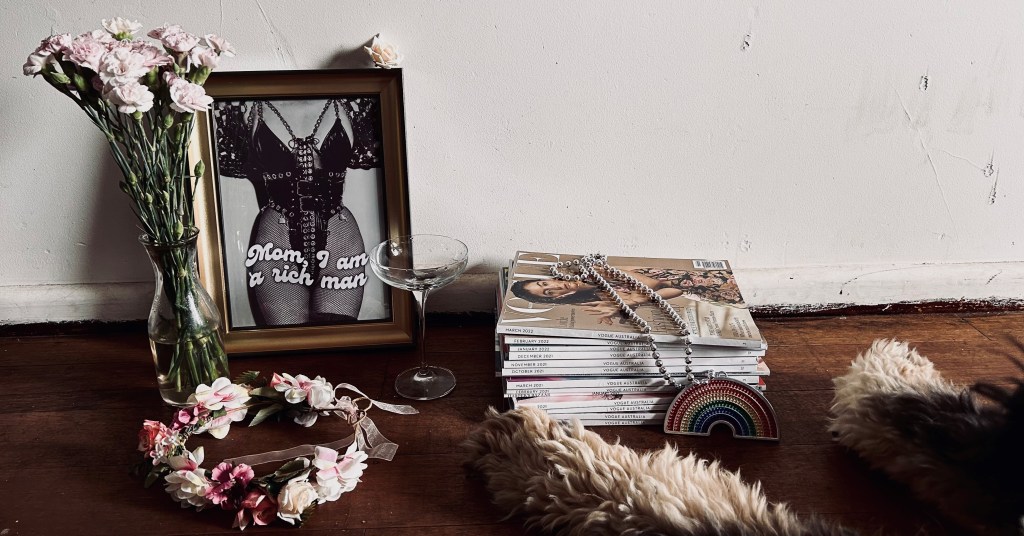 A vase of flowers, a frame, a stack of magazines and a dog lay on the ground.